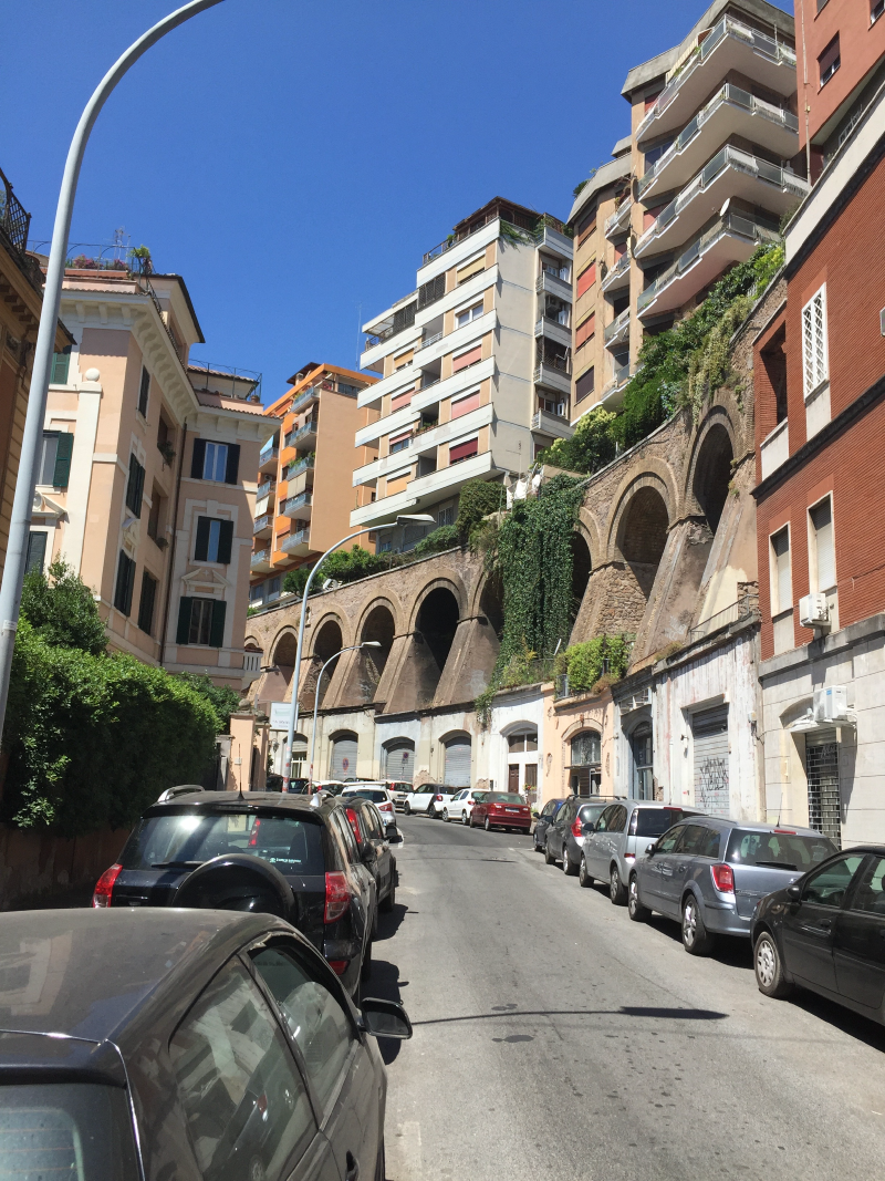 Modern apartment buildings built above old Roman arches along a street