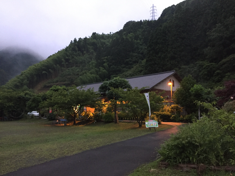 Lit onsen building against forested hillside at dusk
