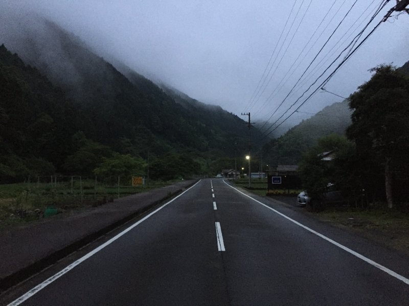 Empty mountain road at dusk with low clouds