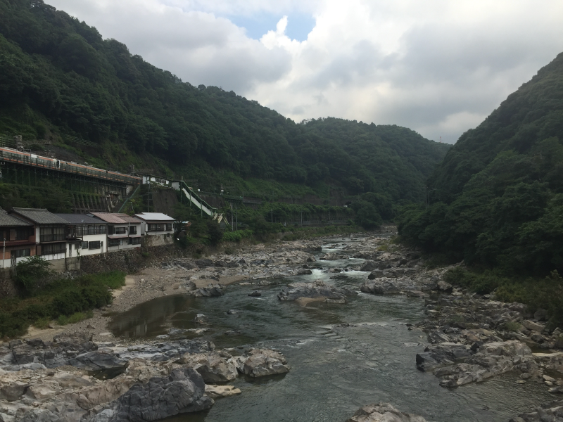 Rocky river flowing through mountain valley with buildings on bank