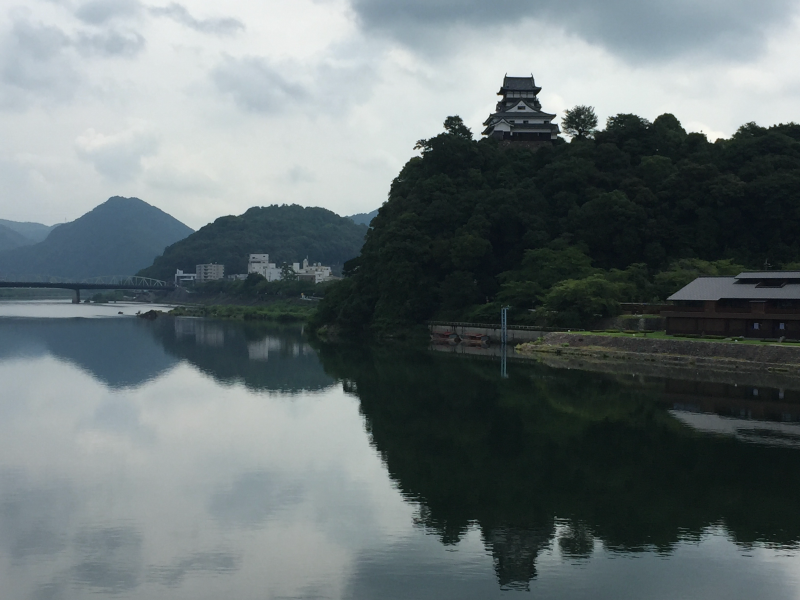 Inuyama Castle perched on wooded hill overlooking mirror-still river