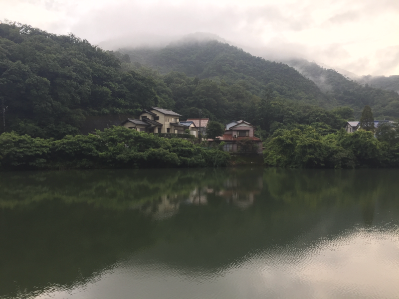 Village houses along misty river with fog-shrouded mountains