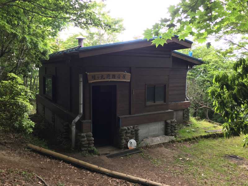 Small wooden emergency shelter hut with Japanese sign above the door