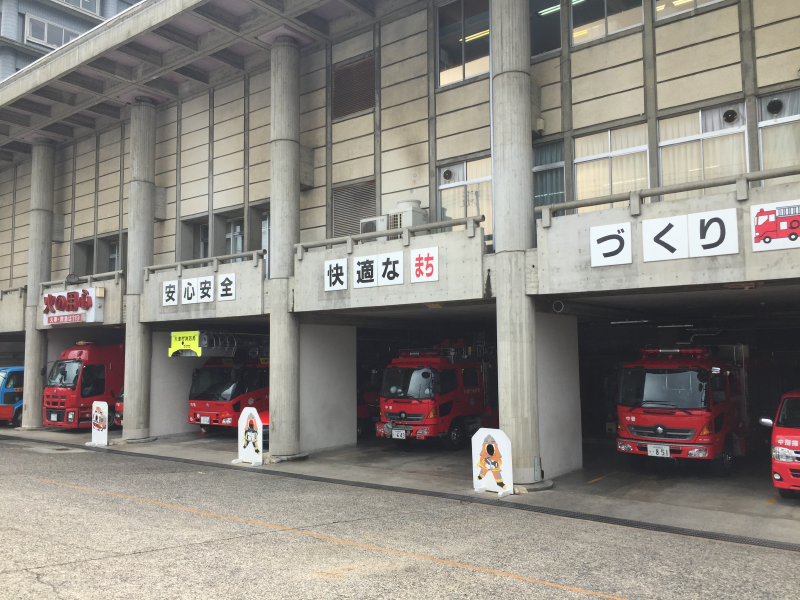 Fire station with red trucks in bays and cartoon firefighter cutouts for children