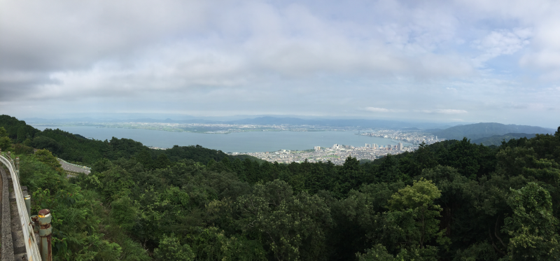 Wide panoramic view of Lake Biwa and coastline from forested ridge
