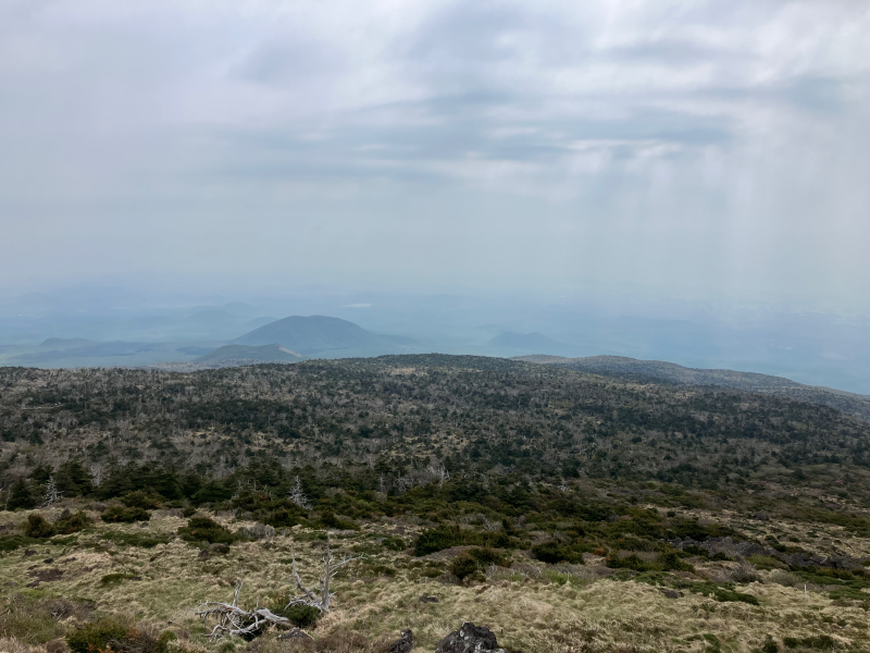 Wide view of low shrubland ridges under cloudy sky