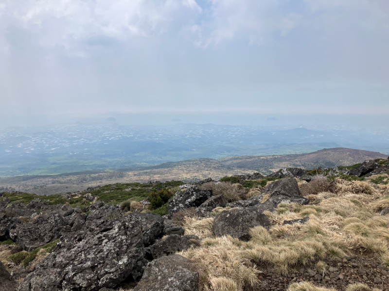 Rocky summit terrain with dry grass and distant haze