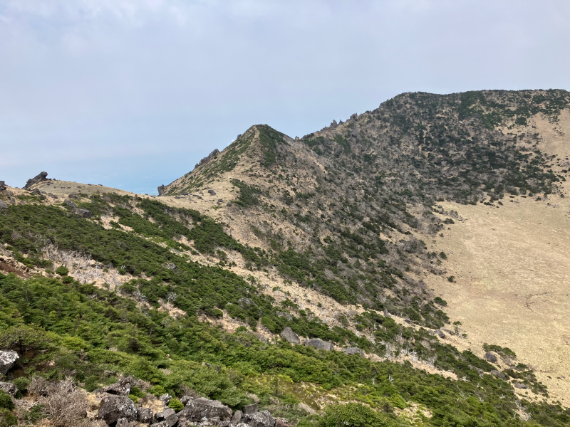 Ridge of crater rim with dry grass slope