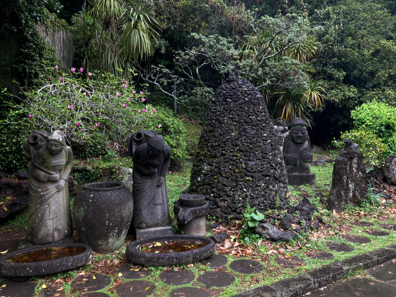 Stone grandfather statues and a volcanic rock cairn in a garden
