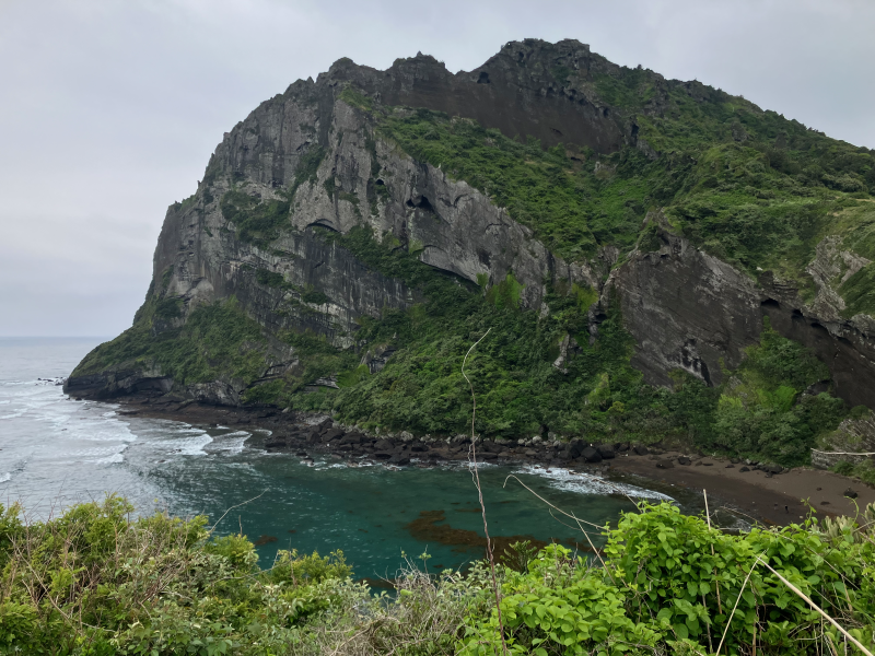 Massive green-cloaked volcanic peak above turquoise bay