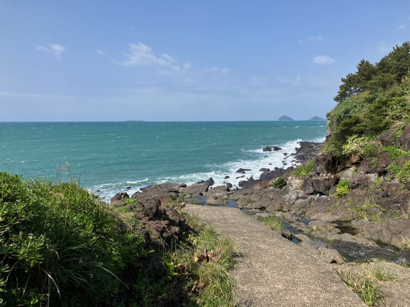Concrete path descending to rocky coast with distant islets