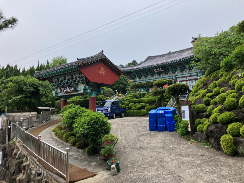 Korean temple gate and buildings with manicured garden and blue truck